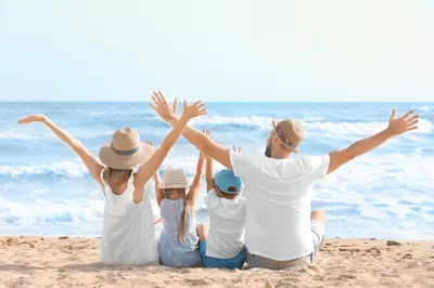 Eine glückliche Familie sitzt am Strand eines Ferienortes