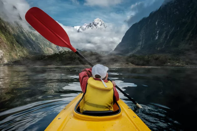 A boy kayaking on a mountain lake.