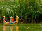 Ein Boot, das auf einem malerischen Fluss in Vietnam treibt, umgeben von üppigem Grün